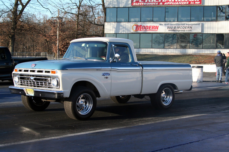 Two-tone white and blue pickup truck with chrome wheels, driving on asphalt