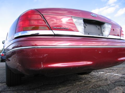2001 Ford Crown Victoria - Rear view of a red 2001 Ford Crown Victoria, showing the taillights and trunk lid badging.