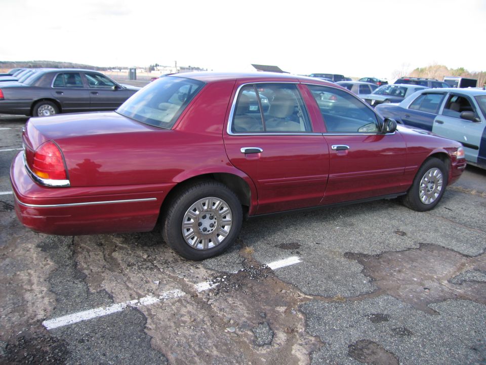 Red sedan parked in a lot with other cars. This is a 2001 Ford Crown Victoria