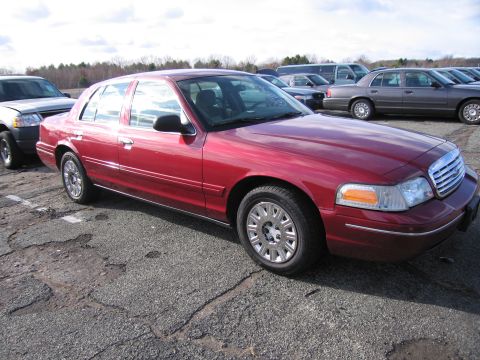 2001 Ford Crown Victoria - A red 2001 Ford Crown Victoria is parked in an outdoor lot with other vehicles.