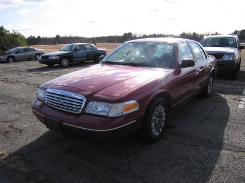 2001 Ford Crown Victoria - A maroon 2001 Ford Crown Victoria is parked in a lot with other vehicles.