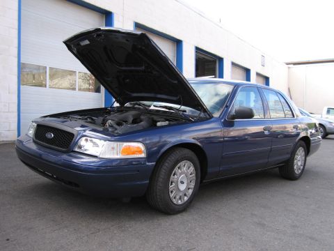 1991 Ford LTD Crown Victoria - A blue sedan, possibly a 1991 model, is parked outside a garage with its hood raised, revealing the engine compartment.