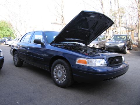 1991 Ford LTD Crown Victoria - Blue sedan with hood open, parked outdoors with other vehicles nearby.