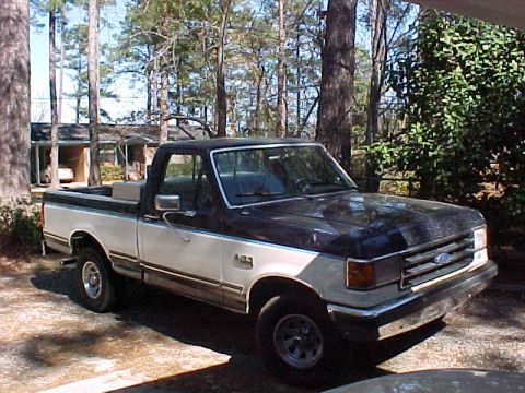 1989 Ford F-150 - This pickup truck has a two-tone paint scheme with a dark blue hood and fenders and a white body.