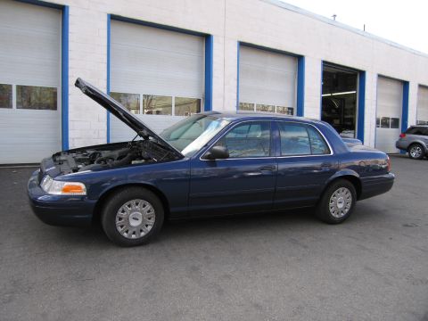 1991 Ford LTD Crown Victoria - A dark blue Ford Crown Victoria sedan is parked outside a garage with its hood open.