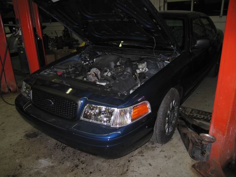 1991 Ford LTD Crown Victoria - Dark blue sedan with hood open, revealing the engine bay. The vehicle is on a lift in what appears to be a garage or repair shop.