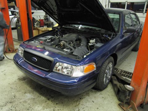 1991 Ford LTD Crown Victoria - Front view of a blue Ford Crown Victoria on a lift, engine compartment exposed.