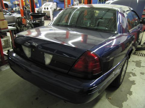 1991 Ford LTD Crown Victoria - Rear view of a dark blue sedan in a garage with the hood open.