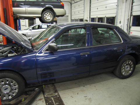 1991 Ford LTD Crown Victoria - A blue 1991 Ford Crown Victoria LTD is shown in a garage with its hood open, while another vehicle is lifted above it.