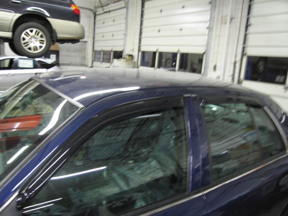 Side view of a dark blue sedan with window visors