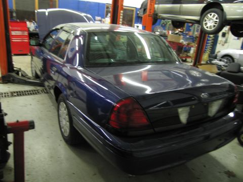 1991 Ford LTD Crown Victoria - A blue sedan is parked in a garage with its hood open and is on a lift.