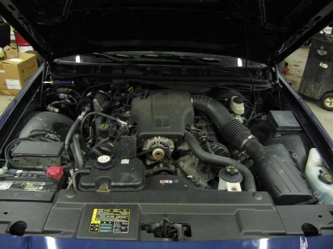 1991 Ford LTD Crown Victoria - Engine bay of a blue Ford Crown Victoria, showing the engine and surrounding components under the open hood.