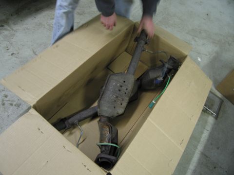 1991 Ford LTD Crown Victoria - A person is handling a catalytic converter inside a cardboard box.