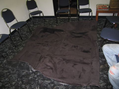 1991 Ford LTD Crown Victoria - A dark carpet is spread out on a patterned floor, with several chairs arranged around it.