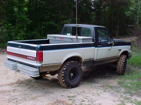 1989 Ford F-150 - This two-tone Ford F-150 pickup truck features a toolbox mounted in the bed and a prominent rear bumper.