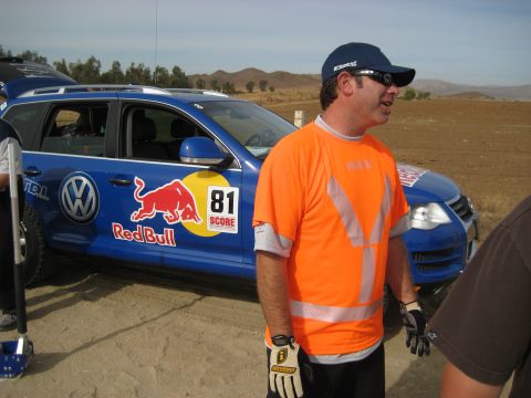 1996 Ford Bronco - A blue Volkswagen SUV, sponsored by Red Bull and displaying racing number 81, is parked on a dirt surface with a man in an orange shirt sta…