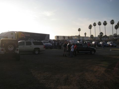 1996 Ford Bronco - A scene with a large truck and multiple vehicles parked in an outdoor lot, with palm trees in the background.