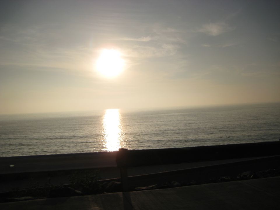 Ocean and sky with sun setting over the water, casting a reflection on the surface