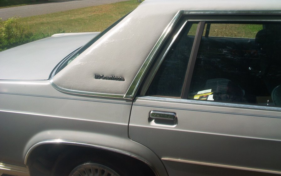 White Ford LTD Crown Victoria side view showing vinyl roof, badge, chrome trim and door handle