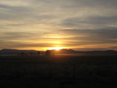 1996 Ford Bronco - Sunrise or sunset viewed over a field with distant mountains and trees.
