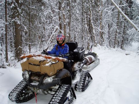 2000 Ford E350 - A person navigates a snow-covered trail on a tracked ATV, with gear loaded on the front.