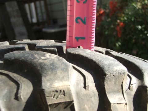 1996 Ford Bronco - A pink ruler measures the tread depth of a tire, indicating its wear level.