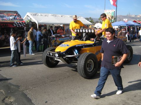 1996 Ford Bronco - A crowd gathers around a bright yellow off-road buggy at an outdoor event.