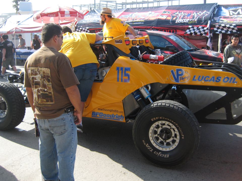 Yellow off-road race truck with number 115 and Lucas Oil sponsorship, front tire visible