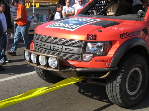 1996 Ford Bronco - Front view of an orange Ford Raptor truck with off-road lights and BFGoodrich tires.