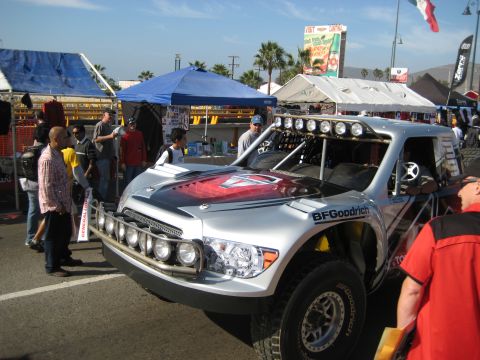1996 Ford Bronco - A custom off-road truck is displayed at an outdoor event with tents and spectators in the background.