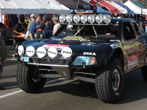 1996 Ford Bronco - A custom off-road truck with numerous sponsor decals and auxiliary lighting is parked outdoors.
