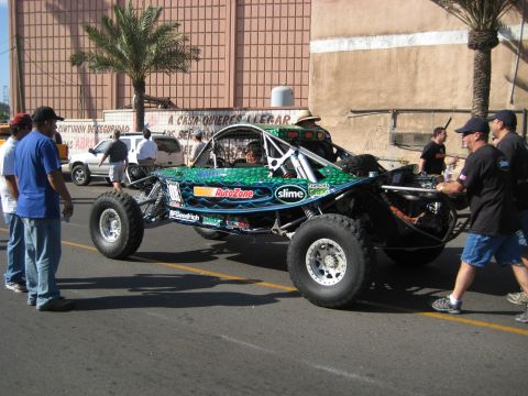 1996 Ford Bronco - Custom off-road buggy with sponsor decals is being pushed by a crew.