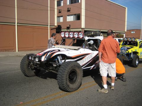 1996 Ford Bronco - Two off-road buggies are parked on a street, with people attending to them.