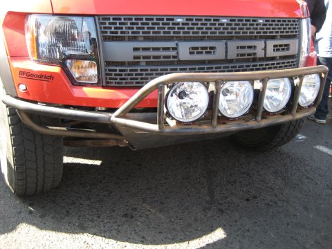 1996 Ford Bronco - Front view of a red Ford Raptor pickup truck with an aftermarket bumper and lights.