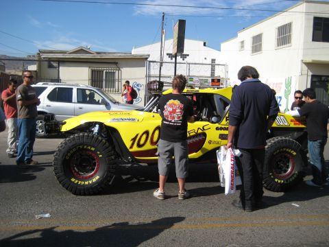 1996 Ford Bronco - A custom-built off-road buggy with racing decals is parked on a street, with several people around it.