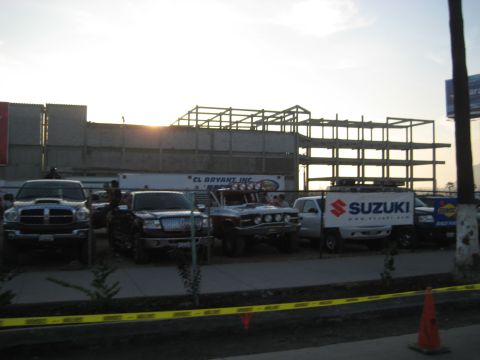 1996 Ford Bronco - Multiple vehicles are parked in front of a construction site with a Suzuki van visible.