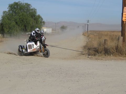 1996 Ford Bronco - A motorcycle with a sidecar navigates a dusty dirt road, with two riders visible.
