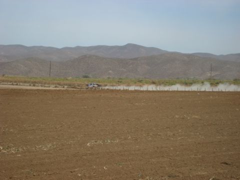 1996 Ford Bronco - A lone off-road vehicle races across a dusty plain, with arid hills in the distance.