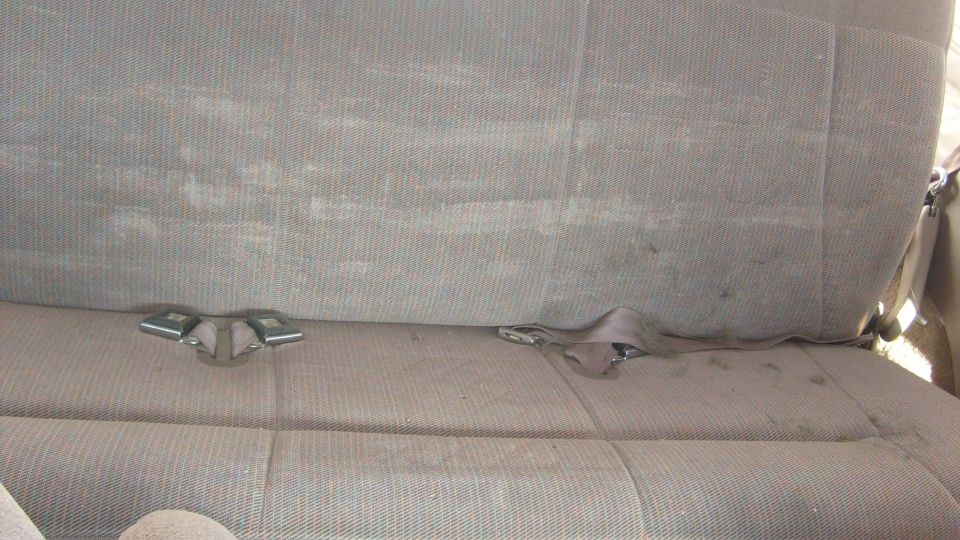 Rear bench seat with two seatbelt buckles visible on the left and one seatbelt strap on the right