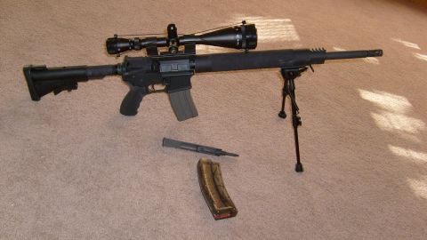 1995 Ford Bronco - A rifle with a scope and bipod is displayed on a carpeted surface next to a detached magazine.