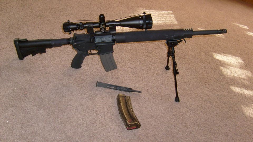 Rifle with scope, bipod, and extra magazine on carpet