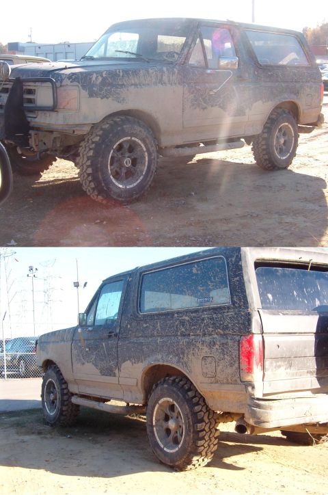1983 Ford Bronco - Mud-covered black Ford Bronco from the front-left quarter, showing aftermarket wheels and a brush guard.