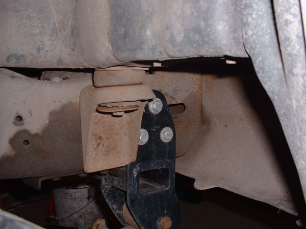 Close-up of a vehicle's frame with a black suspension bracket bolted on