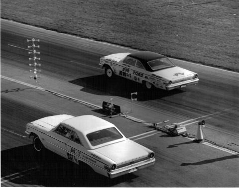 1963 Ford Galaxie - Two cars compete in a drag race, with timing equipment visible on the track.