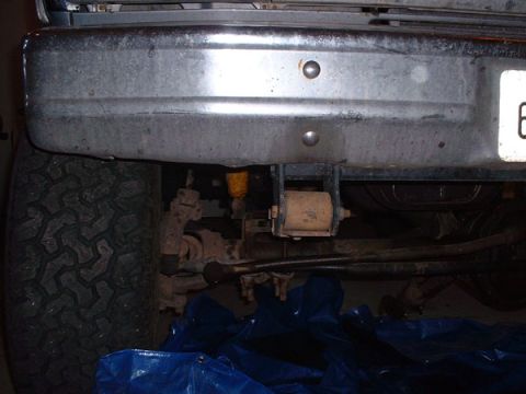 1983 Ford Bronco - The rear of a vehicle is shown, focusing on the bumper, tire, and undercarriage details.