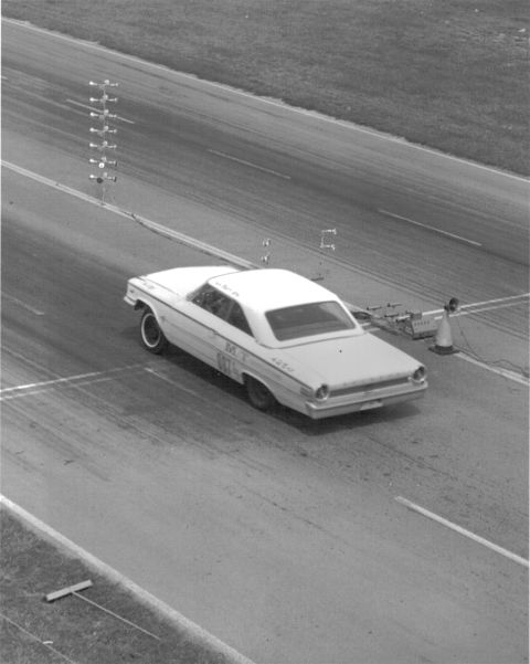 1963 Ford Galaxie - A white 1963 Ford Galaxie coupe is captured from the rear on a drag strip, displaying racing decals.