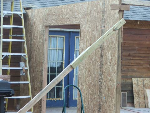 2005 Ford Mustang - A construction project is underway, with a ladder leaning against a wooden structure and plywood covering a doorway.