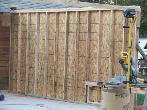 2005 Ford Mustang - A construction scene shows an unfinished wall with exposed studs and plywood, alongside power tools.