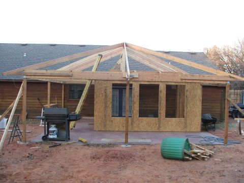 2005 Ford Mustang - A backyard construction project is underway, an unfinished patio roof and various building materials.