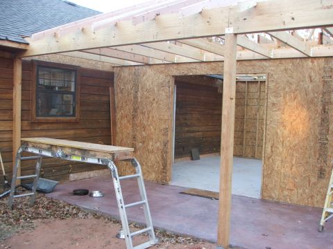 2005 Ford Mustang - An unfinished construction project shows exposed wooden beams and plywood walls, with a ladder and scaffolding in the foreground.